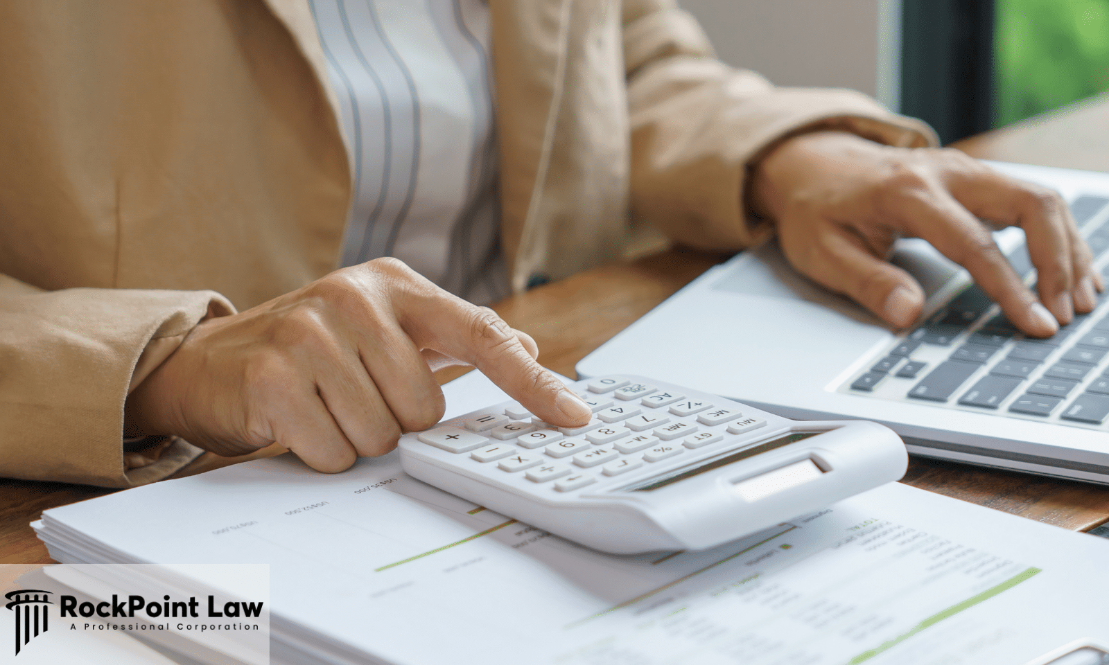 Person using a calculator and laptop to review financial documents