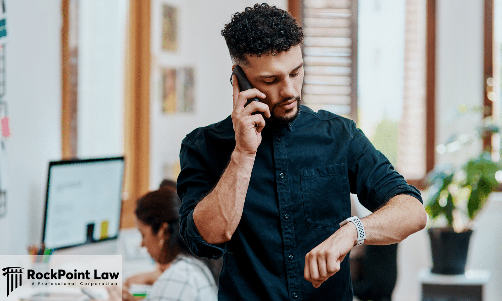 Person checking the time while speaking on the phone about the status of a Lemon Law claim.