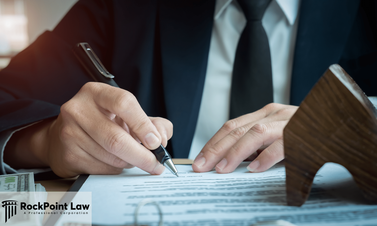 Attorney signing legal documents related to a Lemon Law claim with paperwork and legal files on a desk