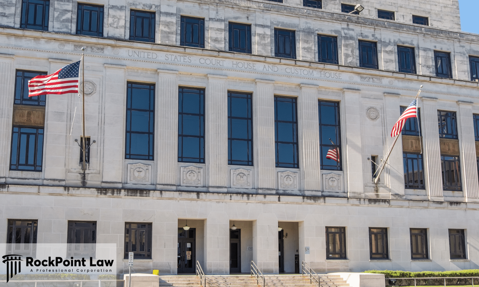 Exterior view of a United States federal courthouse with American flags representing the judicial system