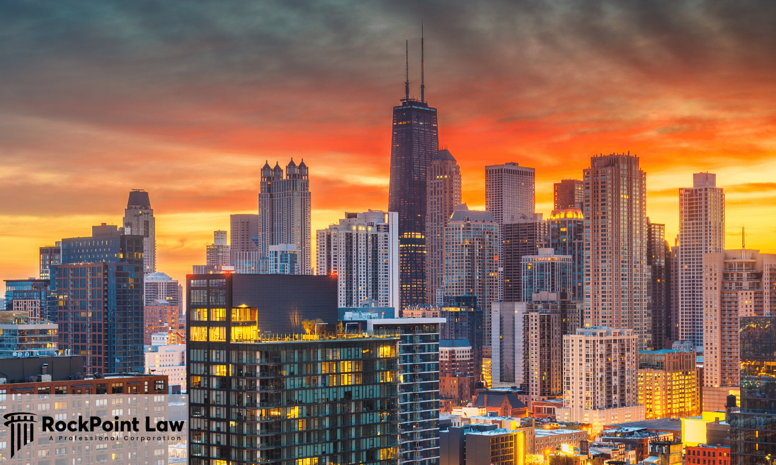 Panoramic view of the Chicago skyline at sunset featuring the John Hancock Center and downtown skyscrapers illuminated against a colorful evening sky.