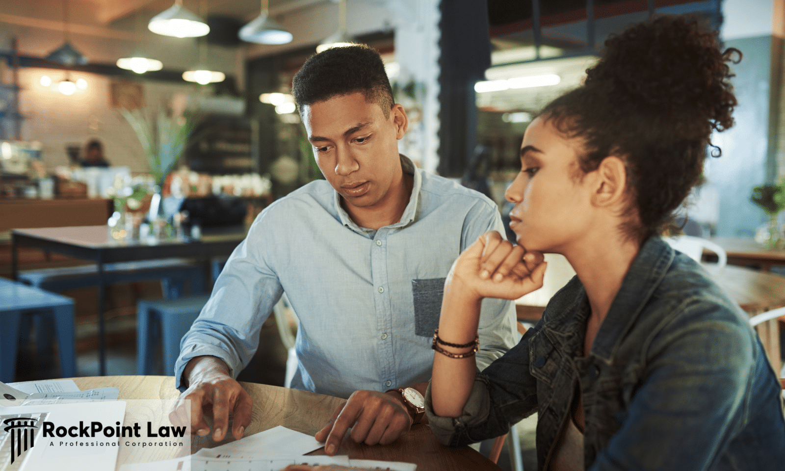 Two consumers reviewing paperwork related to a vehicle purchase before making a buying decision