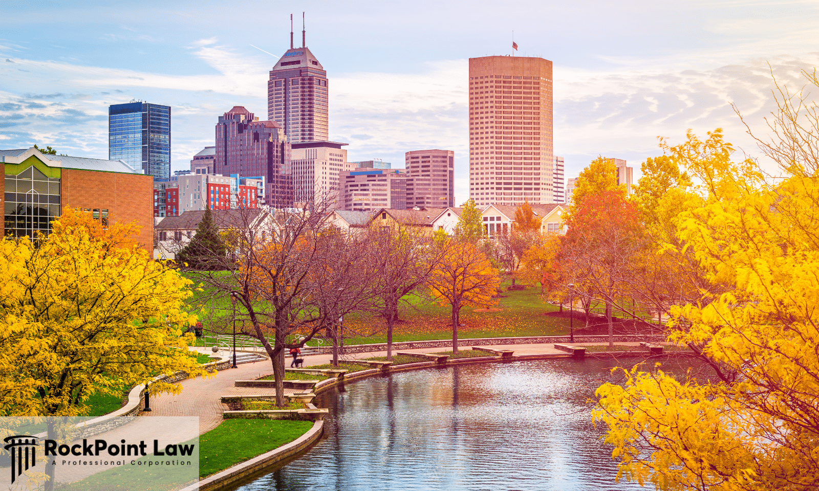 Skyline of downtown Indianapolis, Indiana, viewed from a park with autumn trees and a reflecting pond.