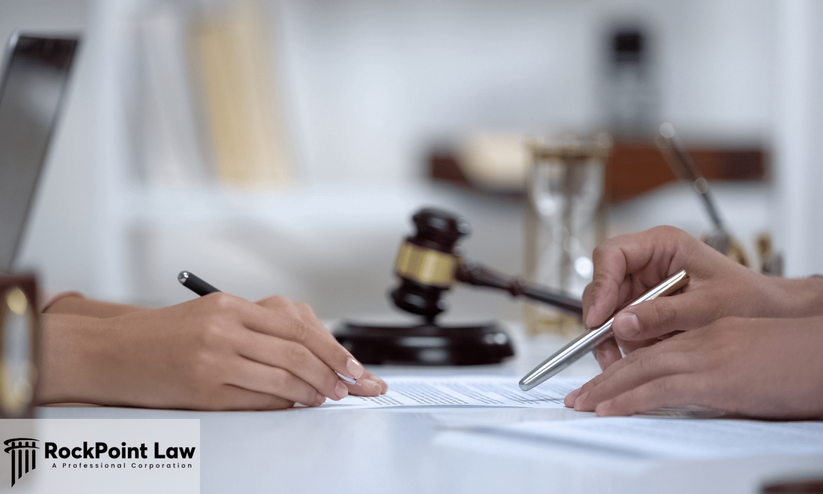 Two people reviewing and signing legal documents with a judge's gavel in the background, representing the Lemon Law claim process.
