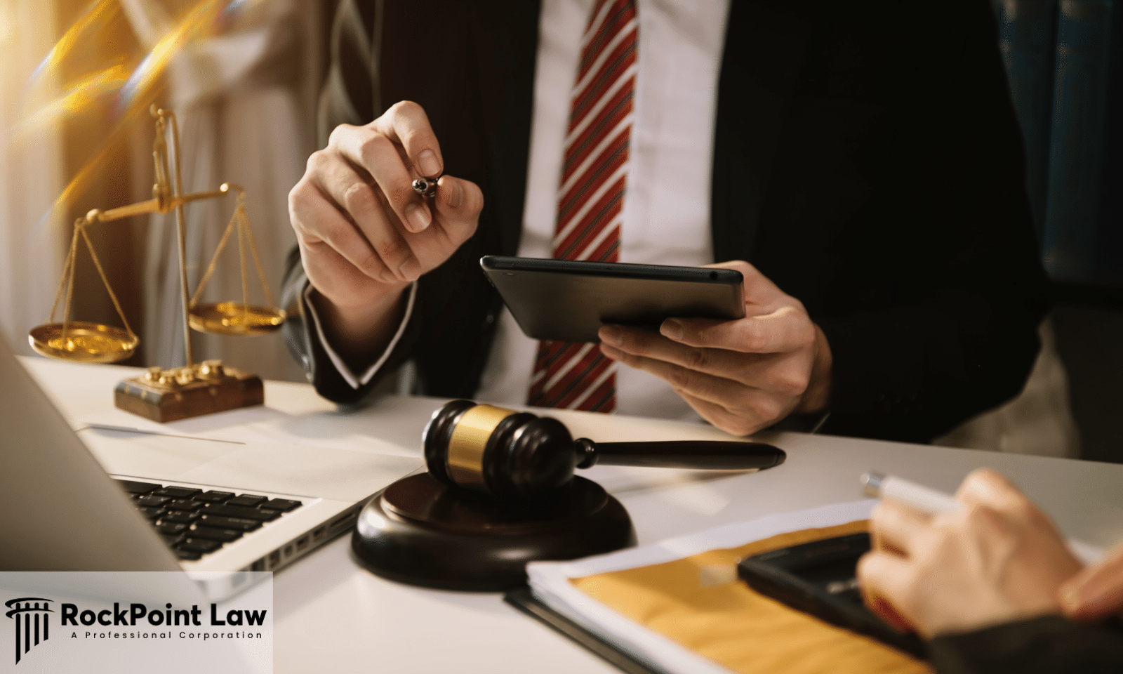 Attorney reviewing Lemon Law documents on a tablet during a client consultation with legal scales and gavel on the desk.