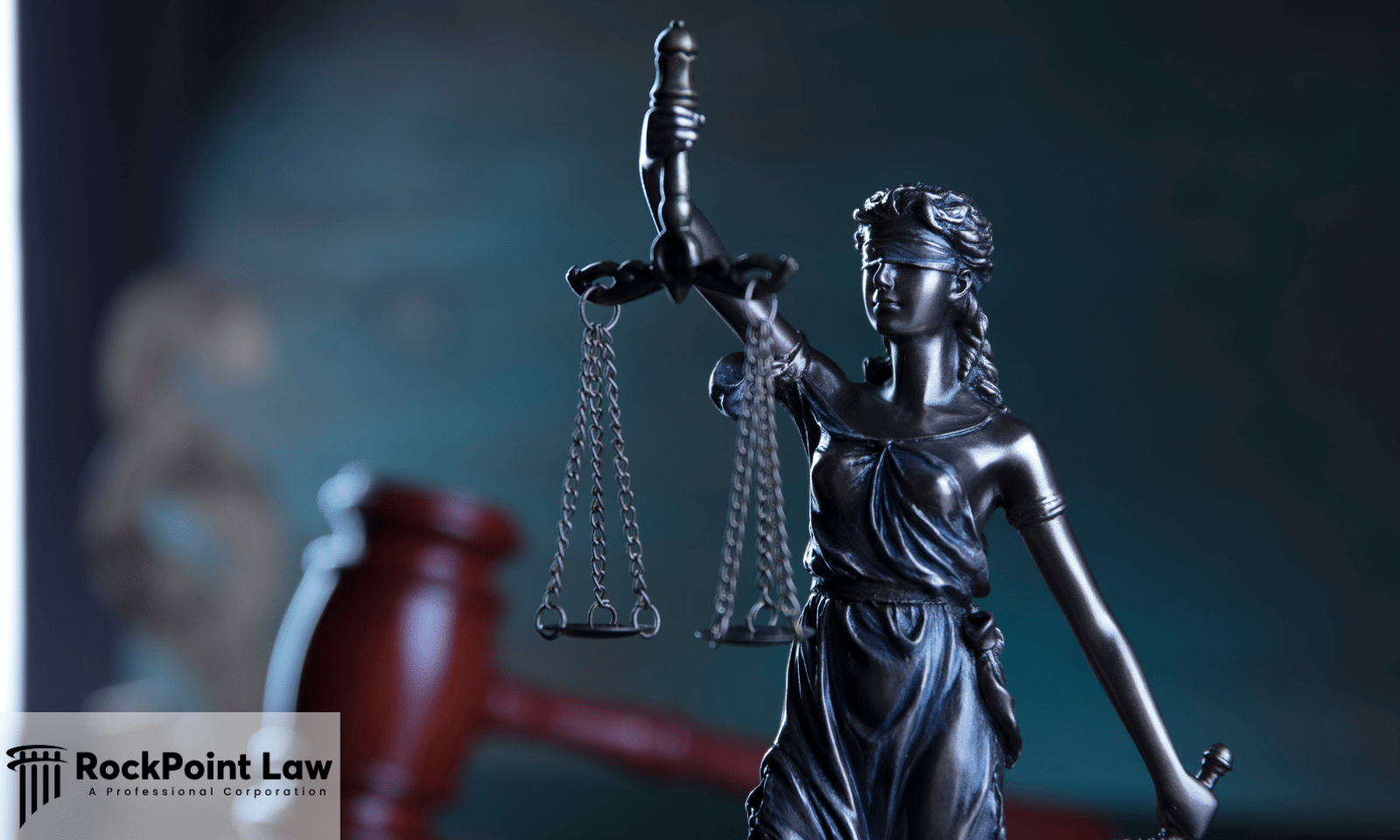 Close-up of the Lady Justice statue with scales of justice and a judge's gavel in the background, symbolizing consumer protection.