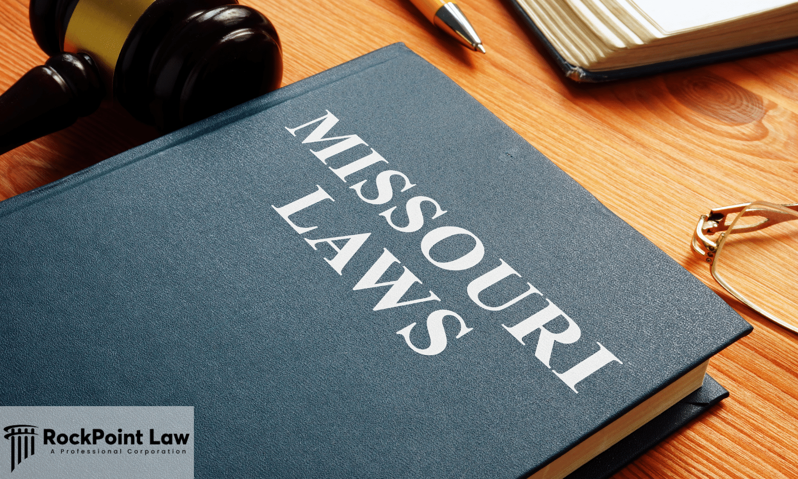 Close-up of a book labeled "Missouri Laws" beside a judge's gavel, eyeglasses, and legal documents on a desk.