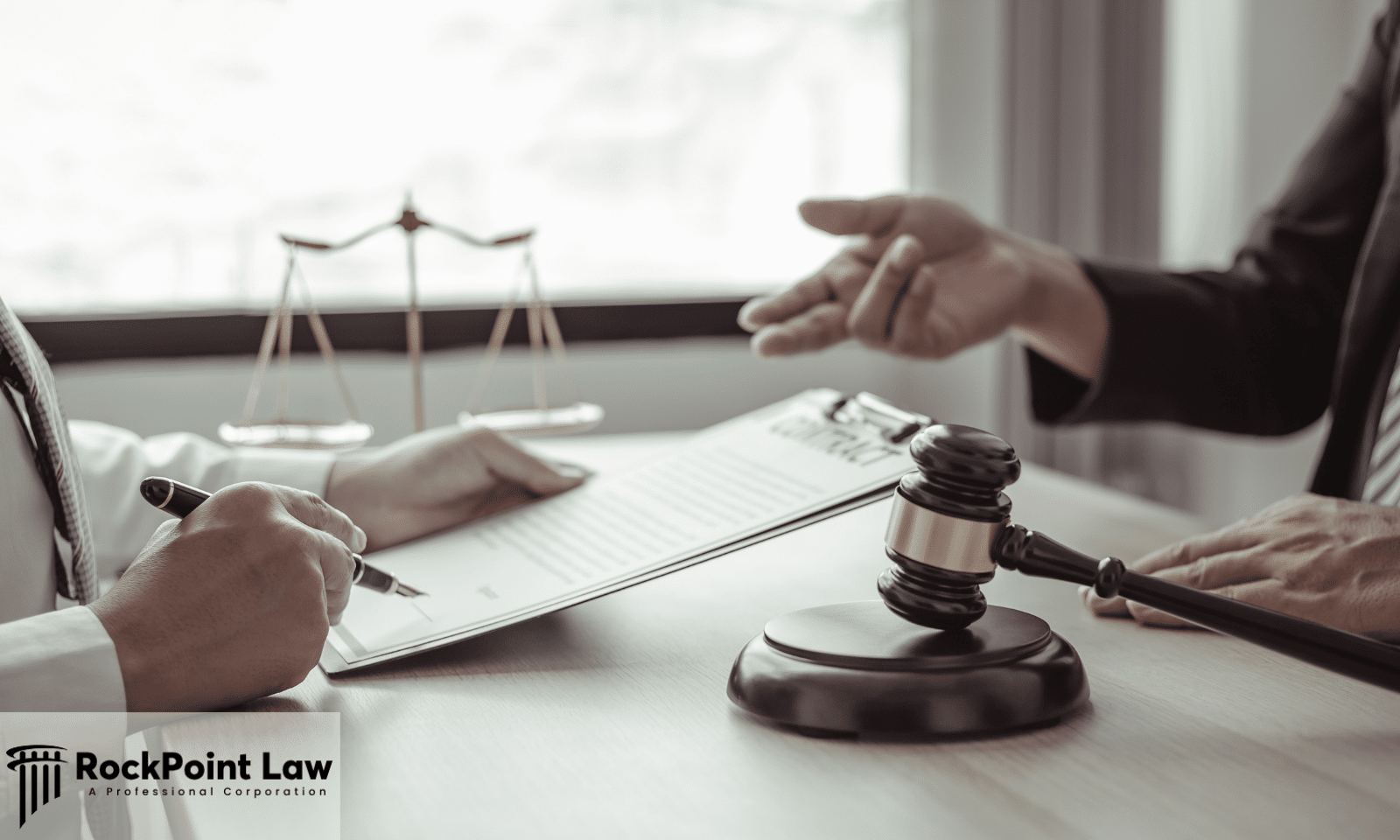 Attorney reviewing and discussing legal documents with a client across a desk beside a judge's gavel.