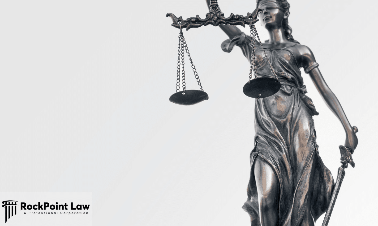 Close-up of the Lady Justice statue holding balanced scales and a sword against a white background.