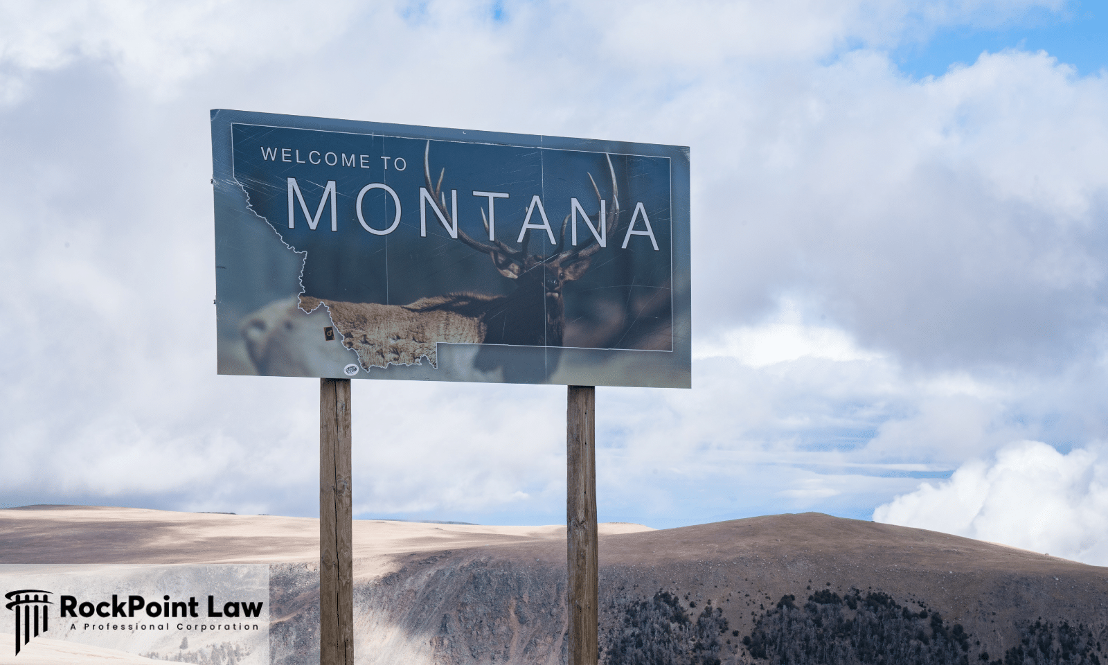 Welcome to Montana roadside sign featuring an elk silhouette against a scenic mountain landscape beneath a clear sky.