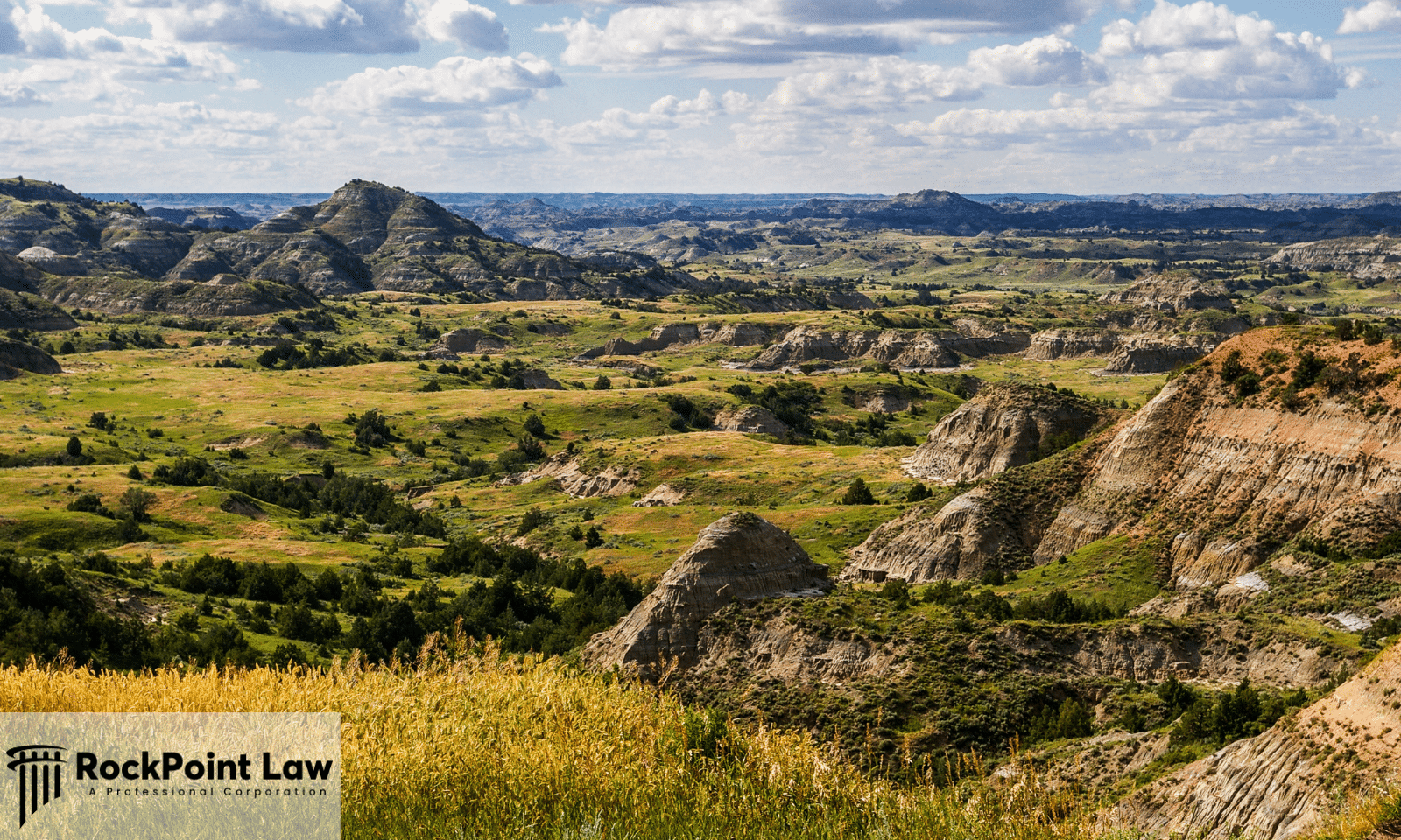 The North Dakota badlands with grassland and layered rock formations under a cloudy sky, illustrating a guide to North Dakota lemon law.