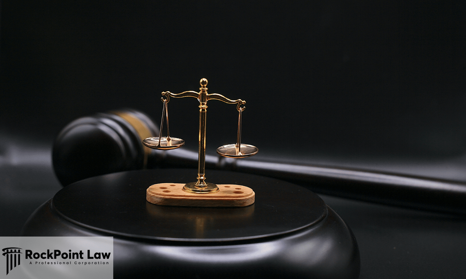 Small scales of justice displayed on a judge's bench with a wooden gavel in the background.