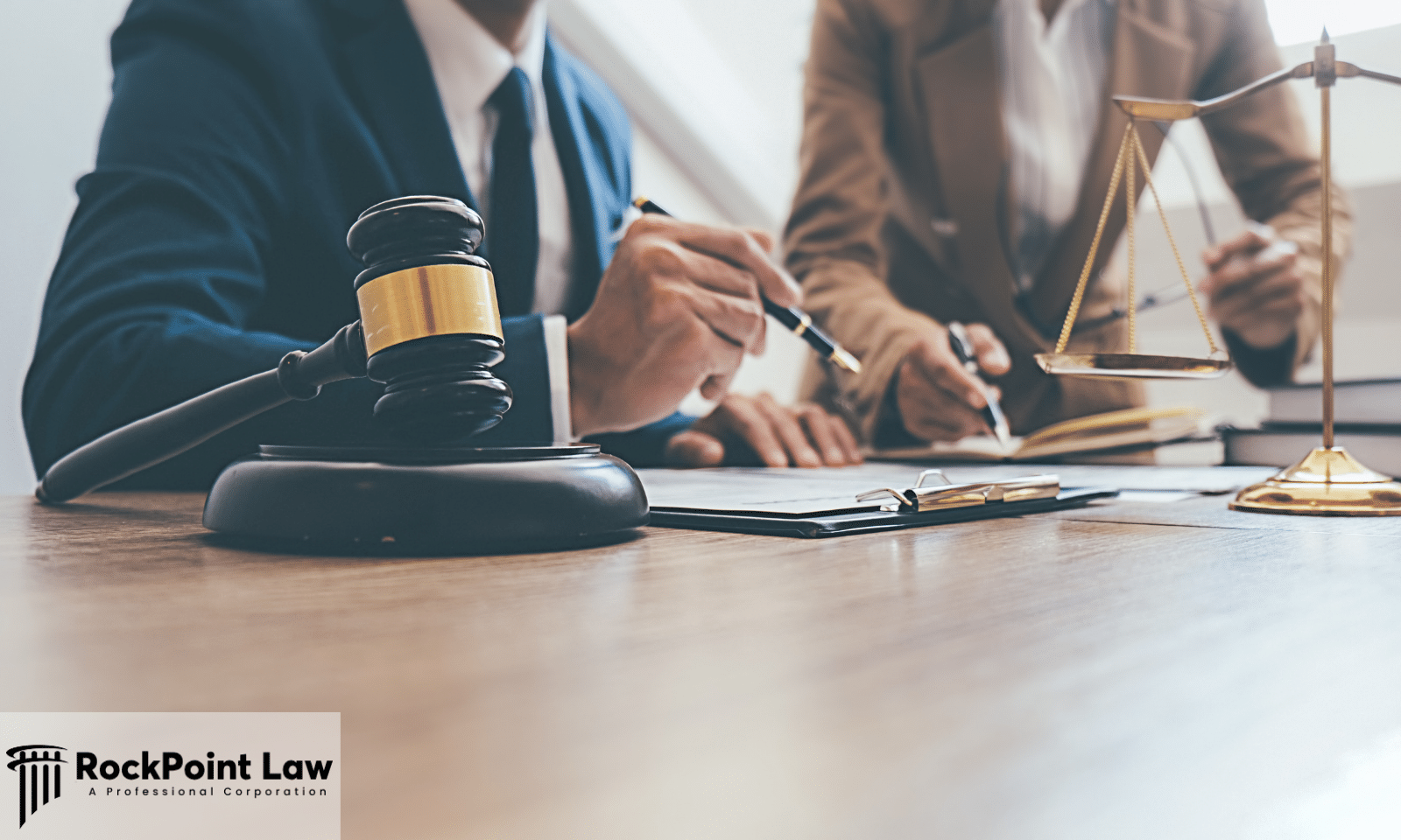 Legal professionals reviewing documents at a desk with a judge's gavel and scales of justice.