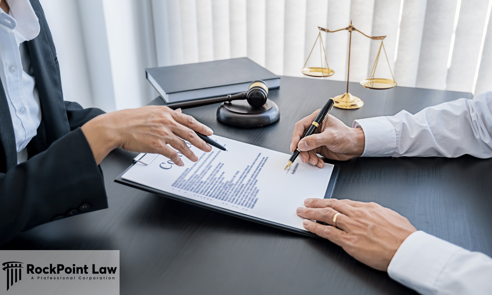 An attorney and client reviewing and signing legal documents across a desk with a judge's gavel.