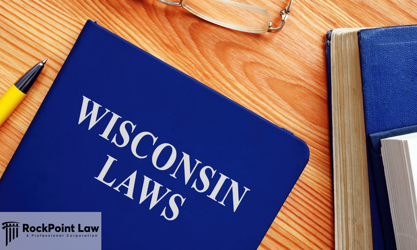 A book titled Wisconsin Laws beside reading glasses and a pen, representing the statute that governs Wisconsin Lemon Law claims.