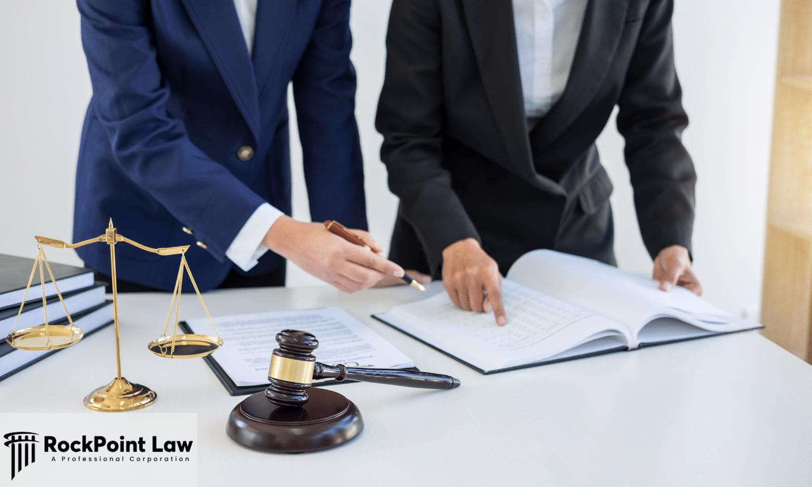 Two attorneys reviewing paperwork beside scales of justice and a gavel, representing the records behind a Wyoming Lemon Law claim.